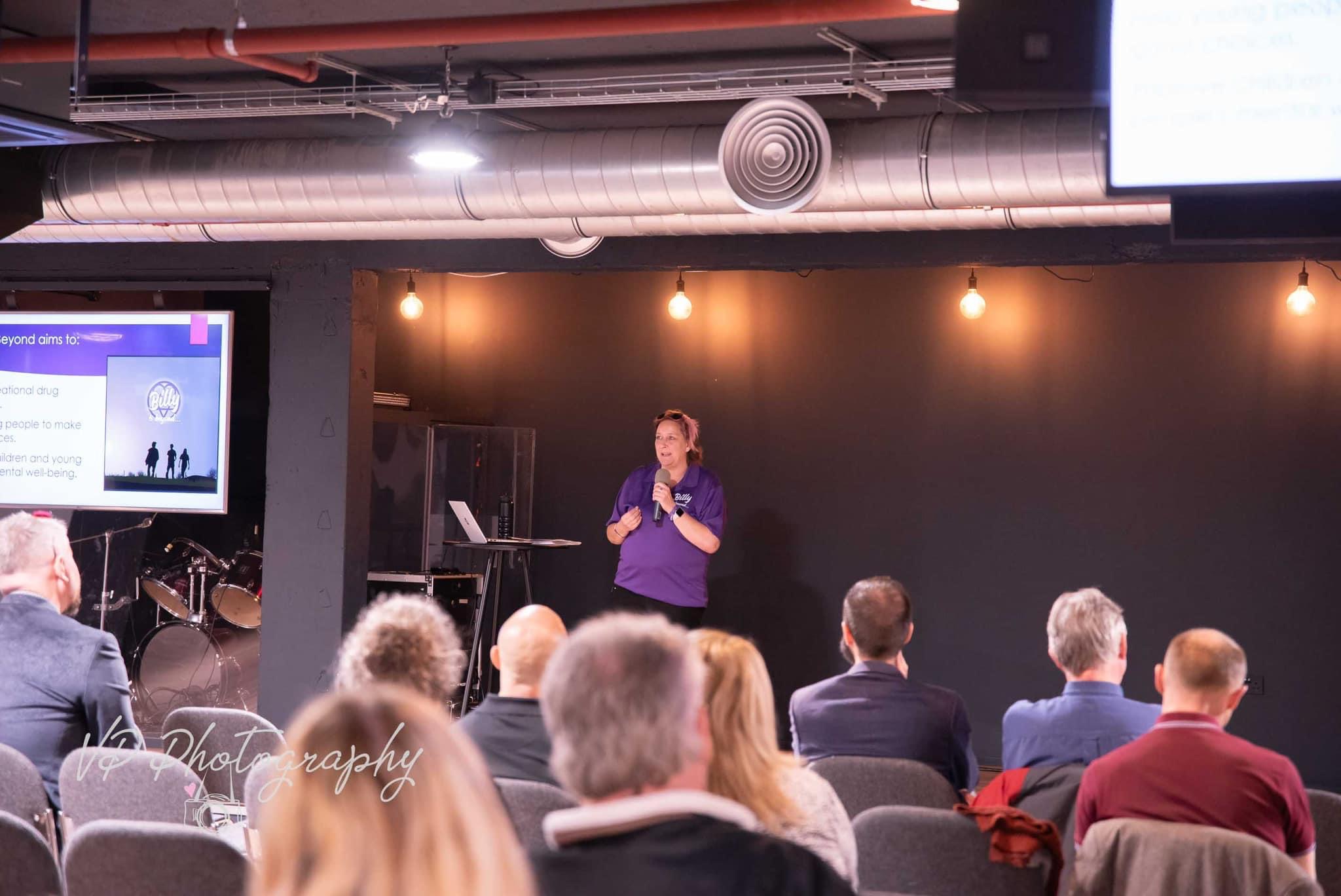 Nicci giving a talk infront of a mixed group of people